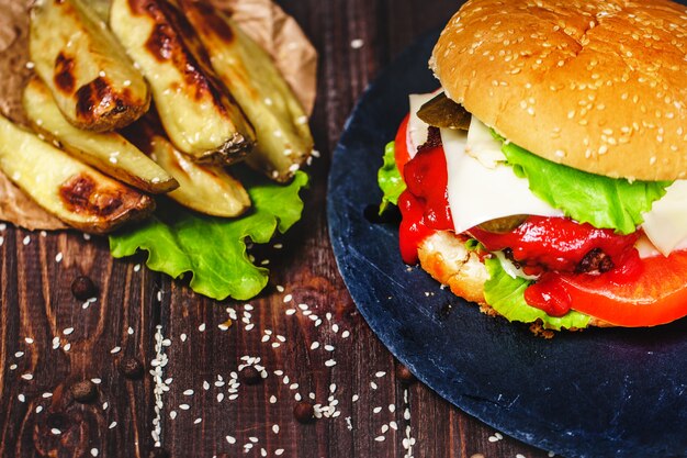 Il primo piano dell'hamburger di manzo fatto casa con lattuga e la patata è servito sul tagliere di pietra.