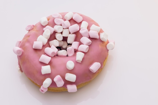 Il primo piano della ciambella rosa su un piatto bianco ruota gli spuntini dolci che cuociono il cibo ad alto contenuto calorico dolce preferito d