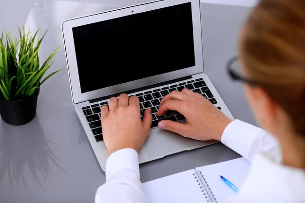 Il primo piano della donna di affari sta digitando sul computer portatile.