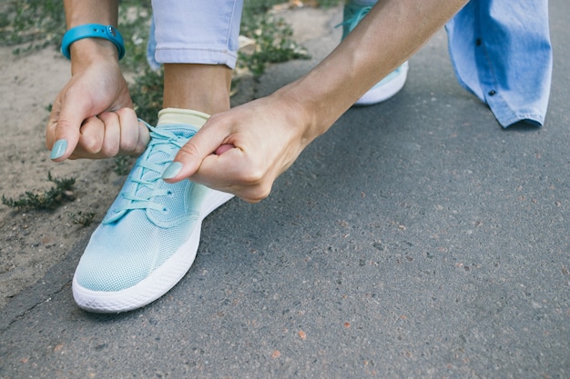 Il primo piano della ragazza lega i lacci sulle scarpe mentre cammina intorno alla città