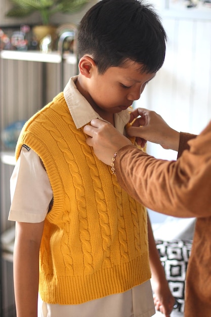 Il primo piano delle mani della madre ha riordinato l'uniforme del figlio al mattino. Ritorno alla preparazione scolastica.