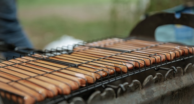 Il primo piano delle salsicce del hot dog è fritto in una griglia sulla griglia.