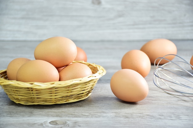 Il primo piano delle uova di pollo / uova di gallina marroni in un canestro di legno con i fieno e le uova del riso