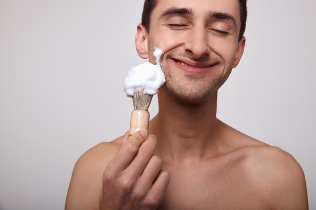 Il primo piano è un uomo felice con schiuma da barba sul viso.