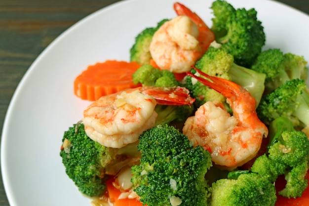 Il primo piano un piatto di scalpore del gamberetto ha fritto con l'aglio e la carota dei broccoli