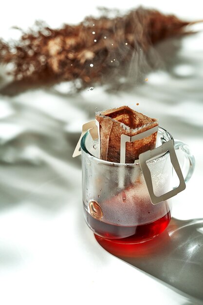 Il processo di gocciolamento del caffè in un bicchiere trasparente. Colazione mattutina soleggiata. Il filtro del caffè