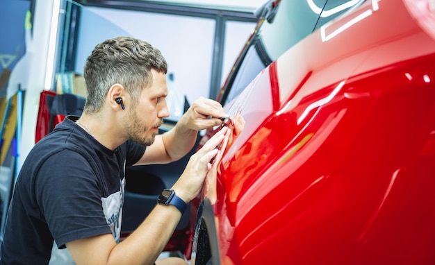 Il processo di installazione del film protettivo sulla nuova auto rossa