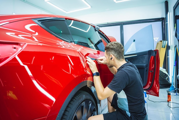 Il processo di installazione del film protettivo sulla nuova auto rossa