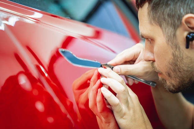 Il processo di installazione della pellicola protettiva sulla nuova auto rossa