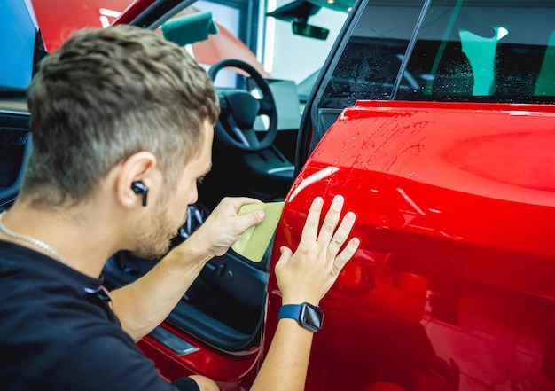 Il processo di installazione della pellicola protettiva sulla nuova auto rossa