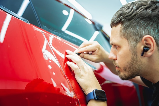 Il processo di installazione della pellicola protettiva sulla nuova auto rossa
