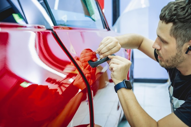 Il processo di installazione della pellicola protettiva sulla nuova auto rossa