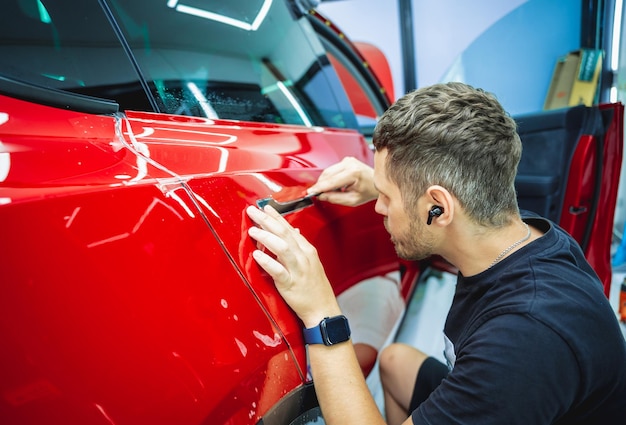 Il processo di installazione della pellicola protettiva sulla nuova auto rossa