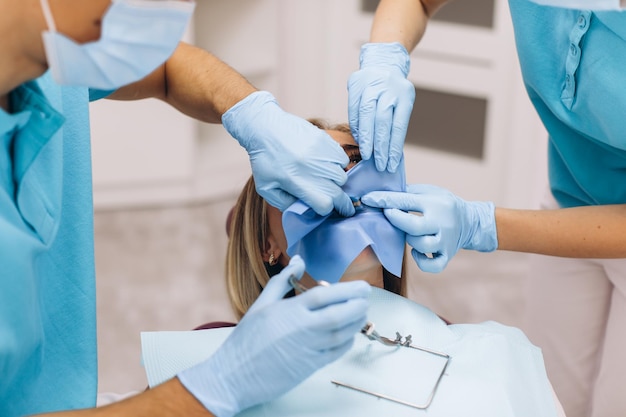 Il processo di isolamento del dente di una donna da parte di due dentisti in una clinica odontoiatrica