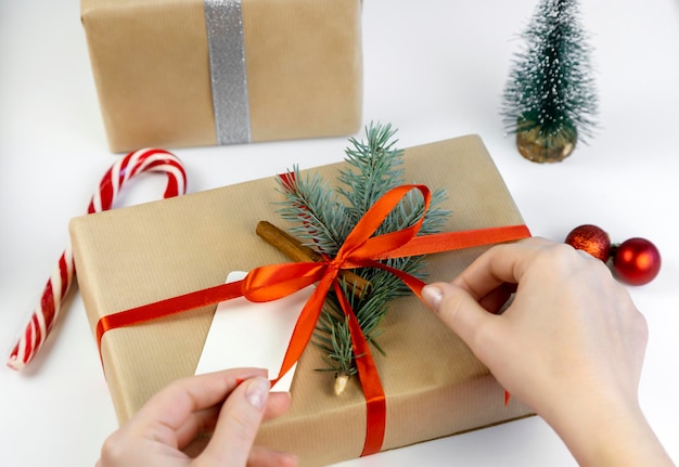 Il processo di legatura di un nastro rosso su una confezione regalo di Natale Concetto di design regalo