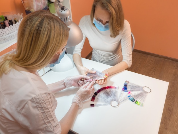 Il processo di manicure. Lavora in una maschera medica.