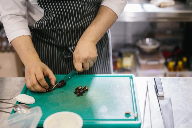 Il processo di preparazione del muesli in un ristorante lo chef maschio taglia i datteri in cucina