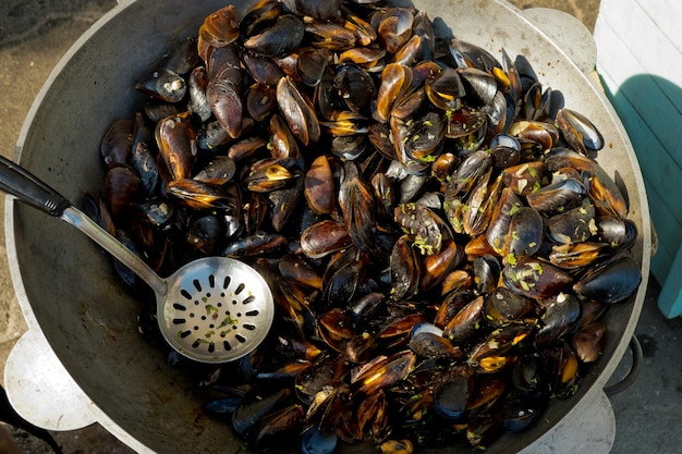 Il processo di preparazione delle cozze in una pentola capiente. Festa del cibo di strada. Messa a fuoco selettiva.