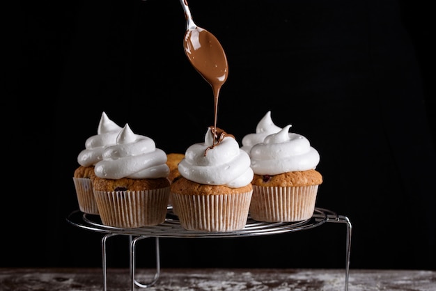 Il processo di preparazione di cupcakes, rivestimento di una crema da una busta di pasta nelle mani di un pasticcere.