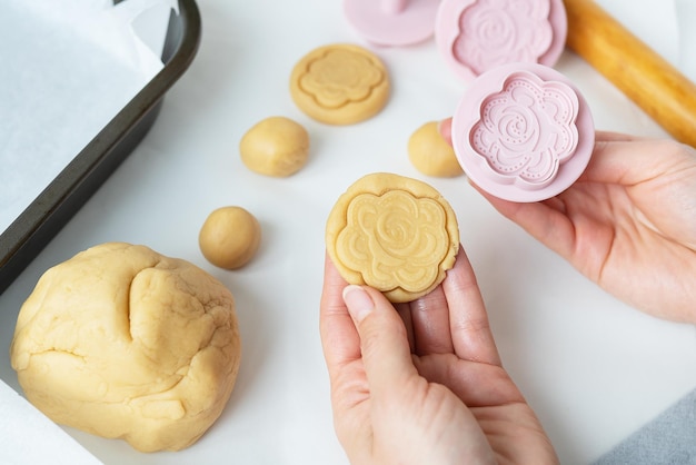 Il processo di realizzazione di biscotti con forme a forma di fiori un mattarello e un vassoio il concetto di cottura in casa