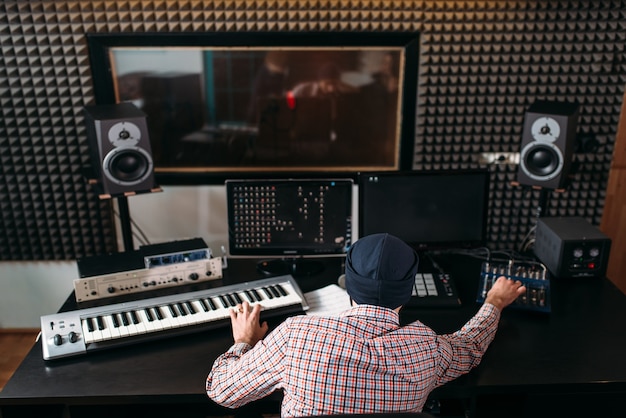 Il produttore del suono lavora con apparecchiature audio in studio.