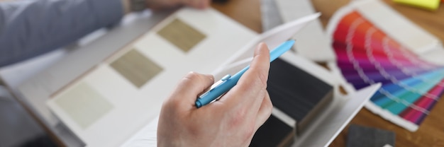 Il progettista dell'uomo sta sfogliando il catalogo con i campioni del primo piano del bordo laminato