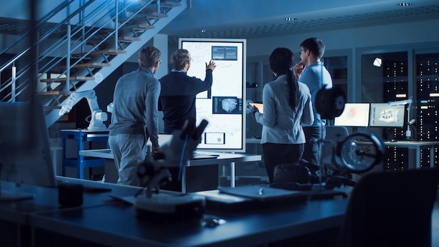 Il project manager fa una presentazione motivazionale o il team di ingegneri di sviluppo elettronico usa la lavagna digitale con la rete neurale AI e l'apprendimento automatico