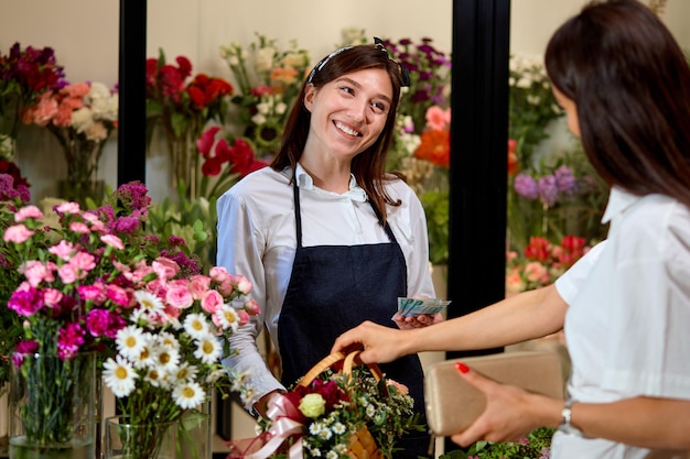 Il proprietario allegro dell'aranceto della donna dell'imprenditore di piccola impresa dà i fiori al cliente