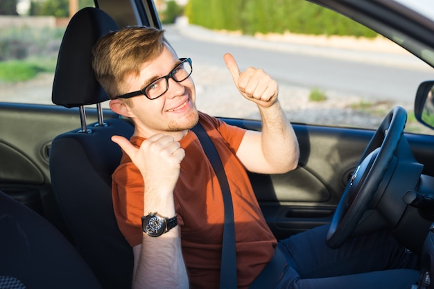 Il proprietario di un'auto felice mostra i pollici in su nella sua nuova auto.