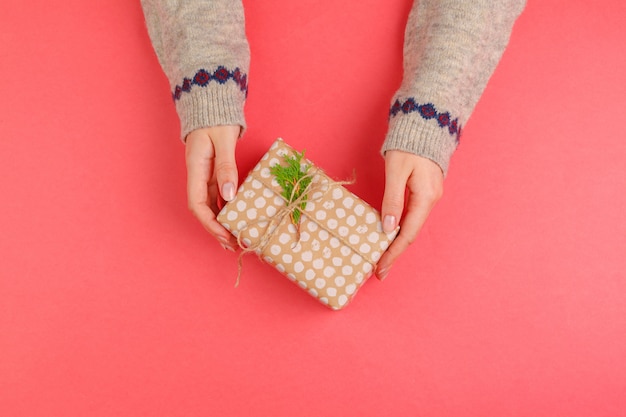 Il punto di vista superiore della donna passa il contenitore di regalo della tenuta su fondo rosa