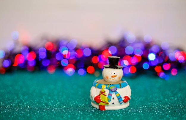 Il pupazzo di neve di Natale sul tavolo contro un bokeh si illumina di nuovo in vacanza