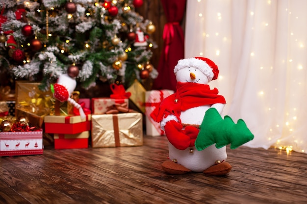 Il pupazzo di neve è cucito, tiene l'albero di Natale