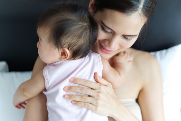 Il raccolto ha sparato di bello bambino asiatico della tenuta della madre sul letto.