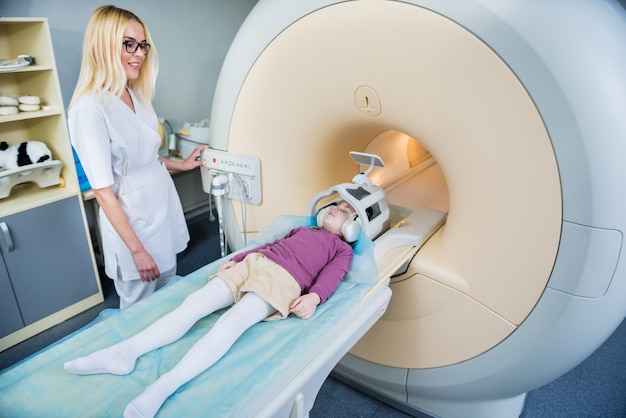Il radiologo prepara la bambina per un esame del cervello di MRI.