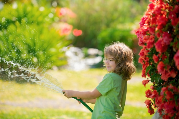Il ragazzino adorabile sta annaffiando la pianta fuori dal concetto di casa di attività di apprendimento della coltivazione delle piante
