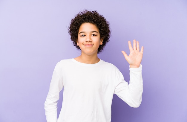 Il ragazzino afroamericano ha isolato il numero di mostra allegro sorridente cinque cinque con le dita.