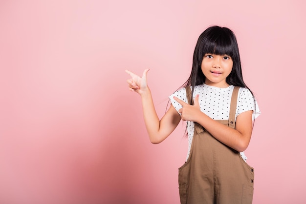 Il ragazzino asiatico di 10 anni punta con il dito indice in alto