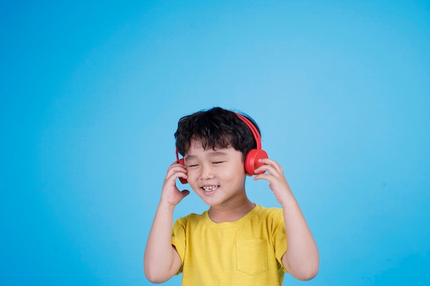 Il ragazzino asiatico felice con le cuffie ascolta la musica