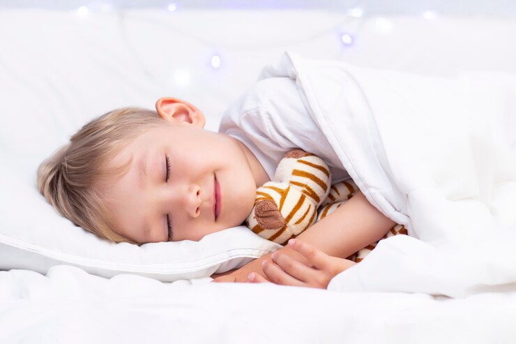 Il ragazzino bianco affascinante dorme a letto. abbraccia un peluche