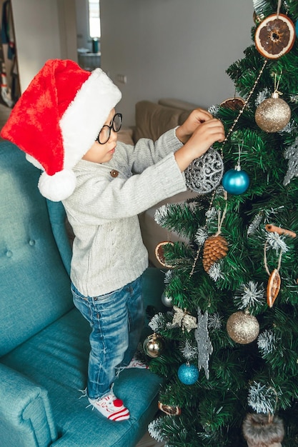 Il ragazzino carino decora un albero di Natale