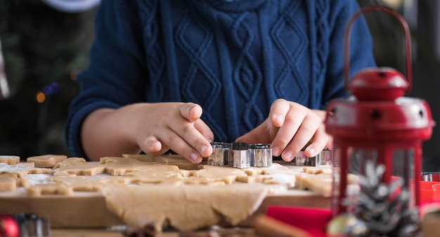 Il ragazzino carino prepara i biscotti di pan di zenzero di Natale nella cucina di Capodanno.