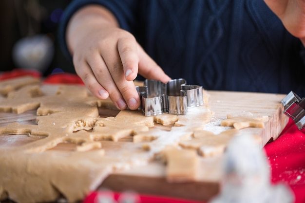 Il ragazzino carino prepara i biscotti di pan di zenzero di Natale nella cucina di Capodanno.