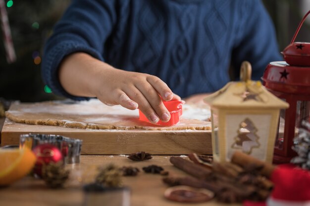 Il ragazzino carino prepara i biscotti di pan di zenzero di Natale nella cucina di Capodanno.