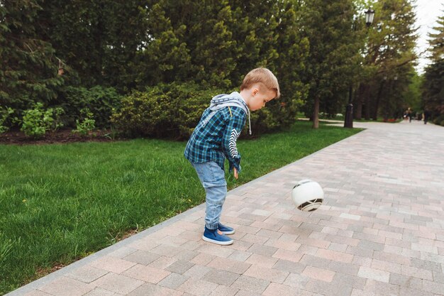 Il ragazzino che gioca a palla nel parco colpisce la palla che attraversa i treni per bambini fieldsport all'aperto