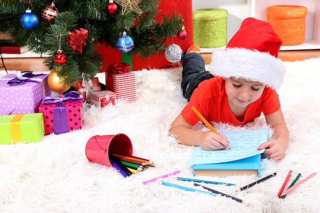 Il ragazzino con il cappello di Babbo Natale scrive una lettera a Babbo Natale