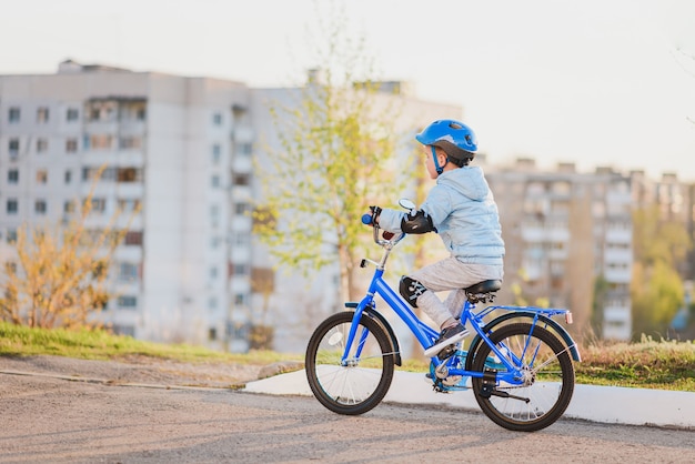 Il ragazzino con il casco va in bicicletta in una giornata di sole