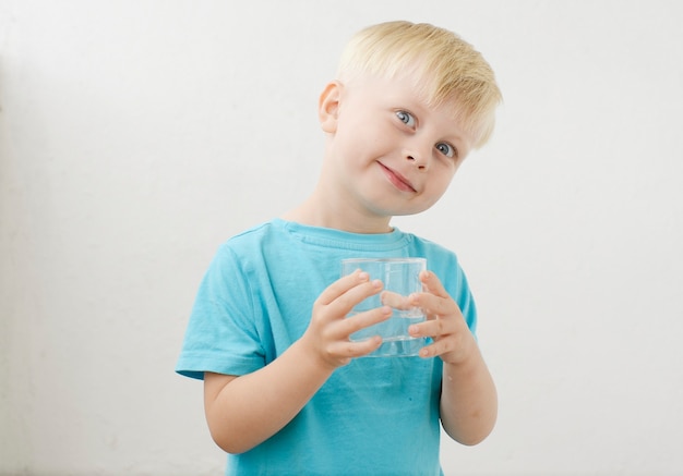 il ragazzino con una maglietta blu beve acqua