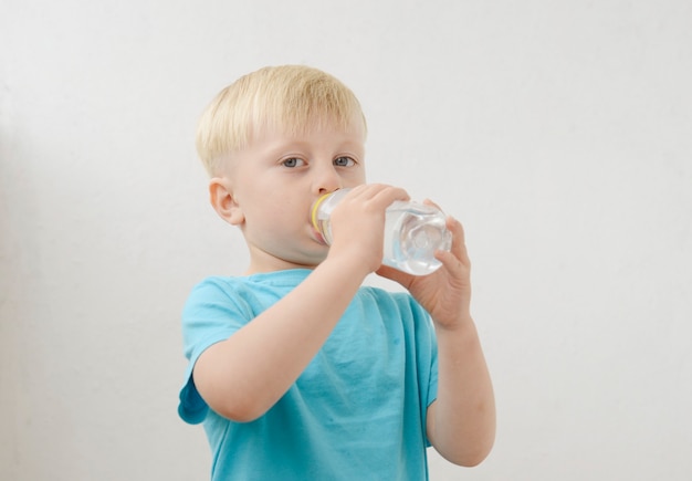 il ragazzino con una maglietta blu beve acqua