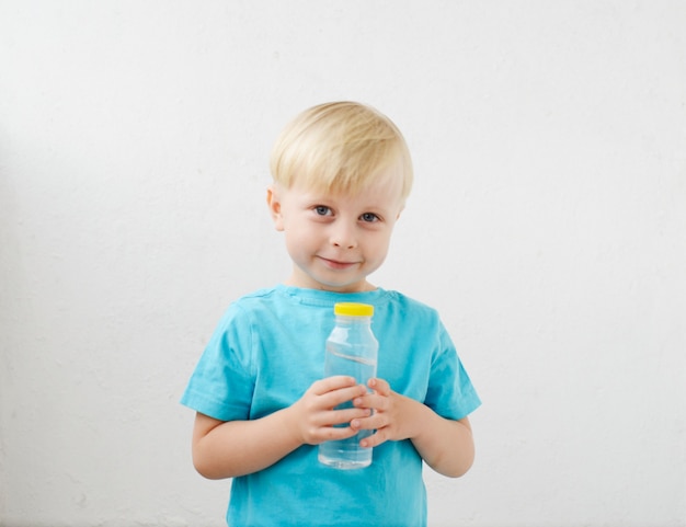 il ragazzino con una maglietta blu beve acqua