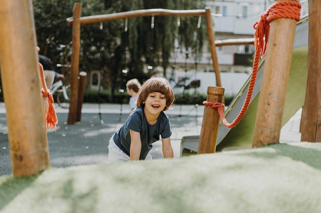 Il ragazzino con una maglietta blu e pantaloncini bianchi è seduto sull'erba verde nel parco giochi. il bambino trascorre attivamente il tempo giocando e camminando all'aperto. stile di vita. spazio per il testo. Foto di alta qualità